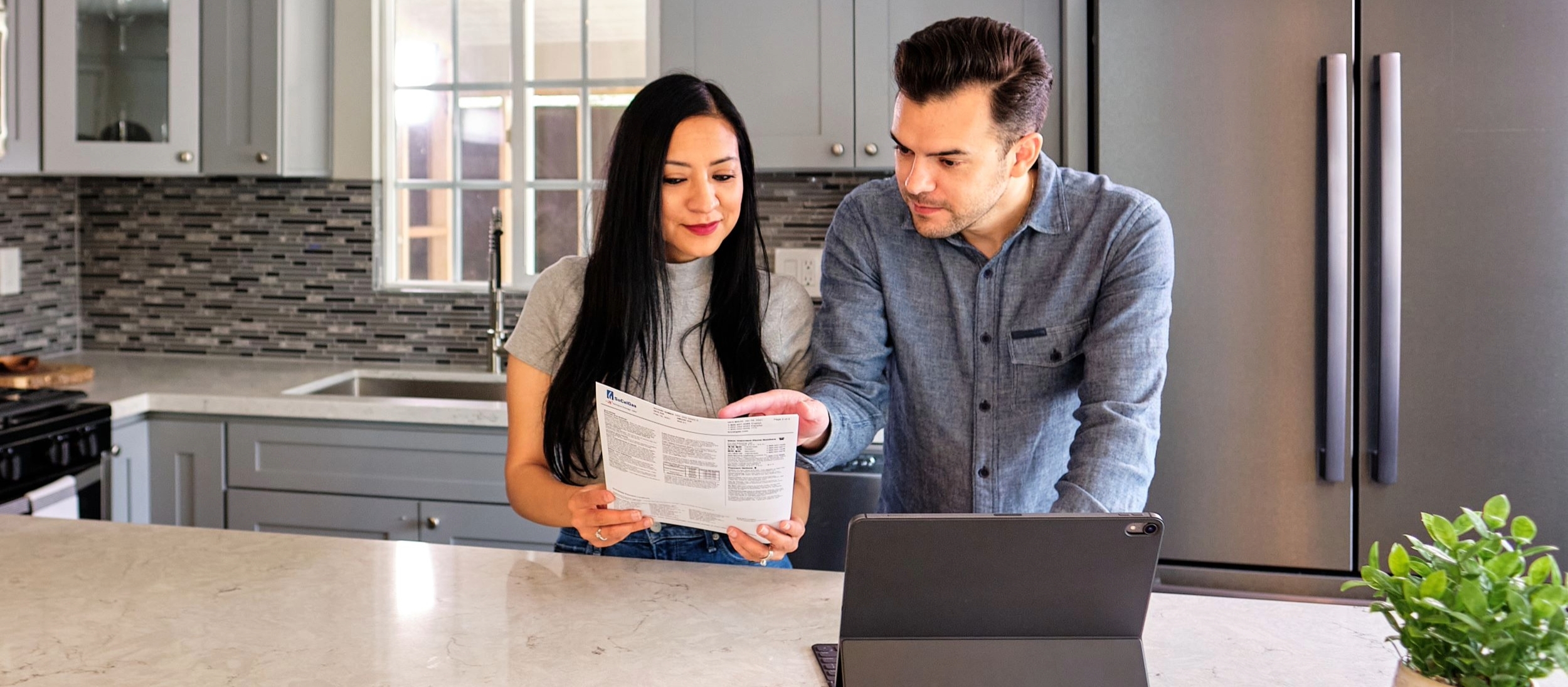 Two people looking at their utility bill in the kitchen