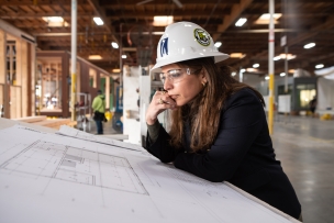 Woman in hard hat looking at blueprints
