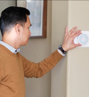 Man adjusting temperature on a thermostat