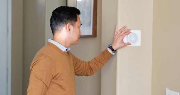 Man adjusting temperature on a thermostat